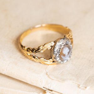 Antique Georgian forget-me-not ring with a cameo centre, diamond halo and intricately decorated yellow gold shoulders.
