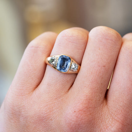 Close up of sapphire ring with diamond side stones showing soft blue tone.