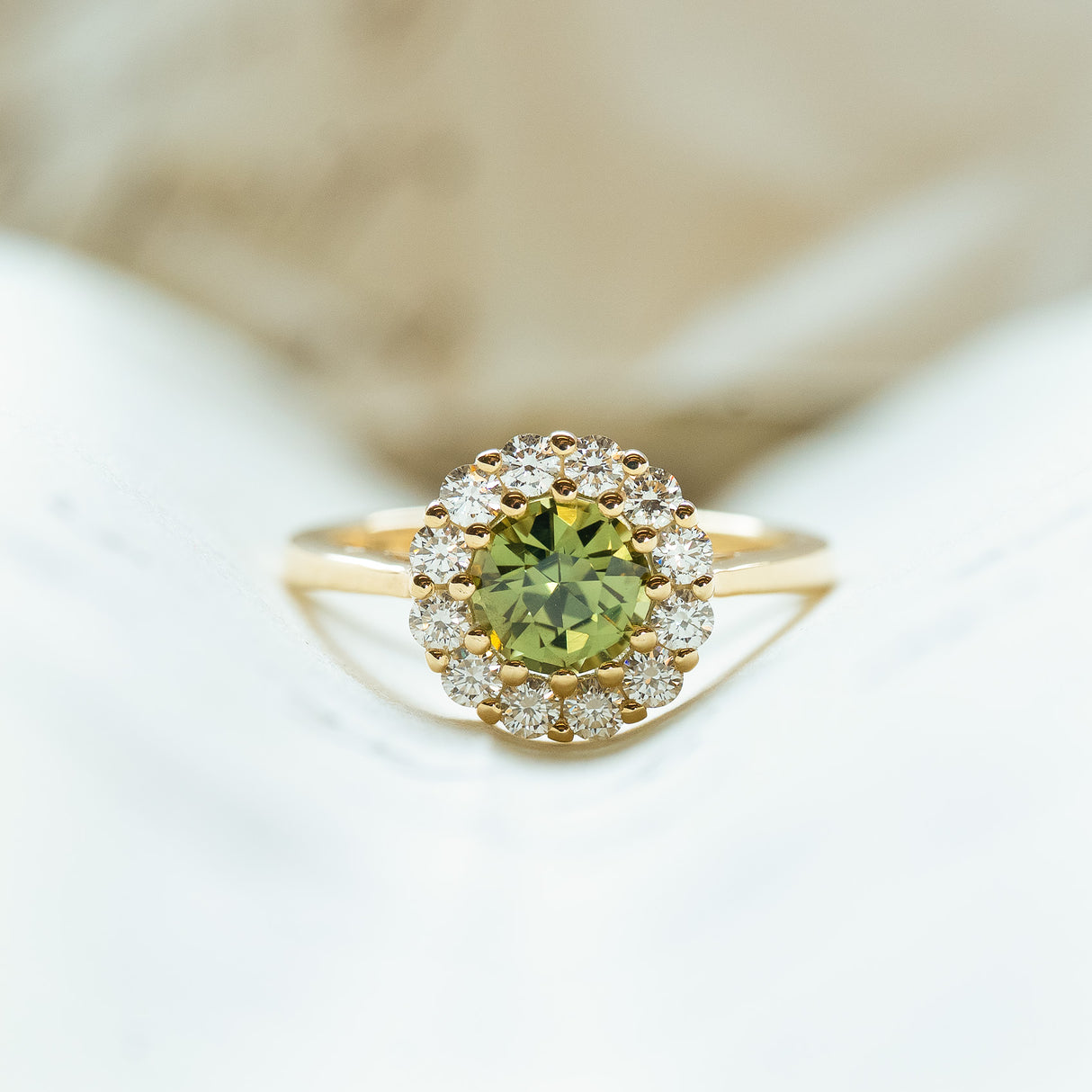 Green sapphire and diamond cluster engagement ring styled on open book pages.