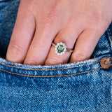 Green sapphire cluster ring worn on hand with denim pocket detail.