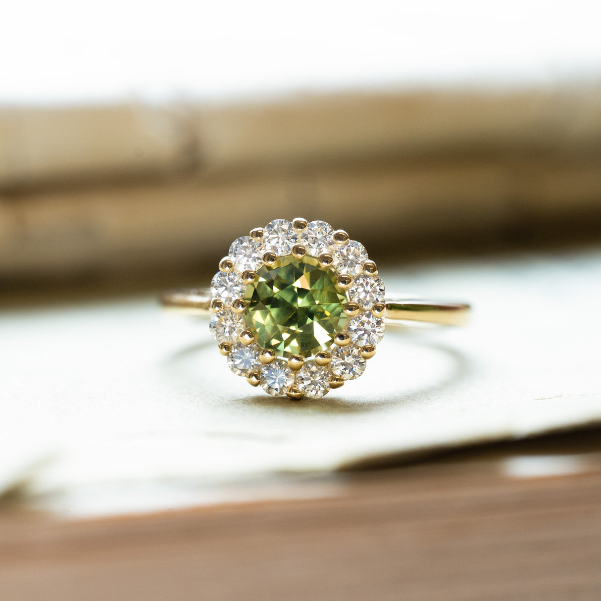 Green sapphire and diamond cluster engagement ring with sparkling diamond halo and slim gold band.