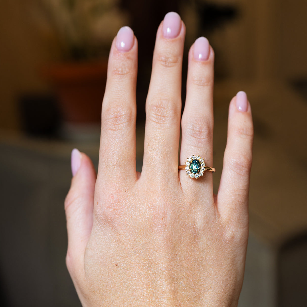 Green sapphire cluster ring worn on hand with natural manicure.