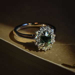 Green sapphire engagement ring with oval gemstone and diamond cluster halo