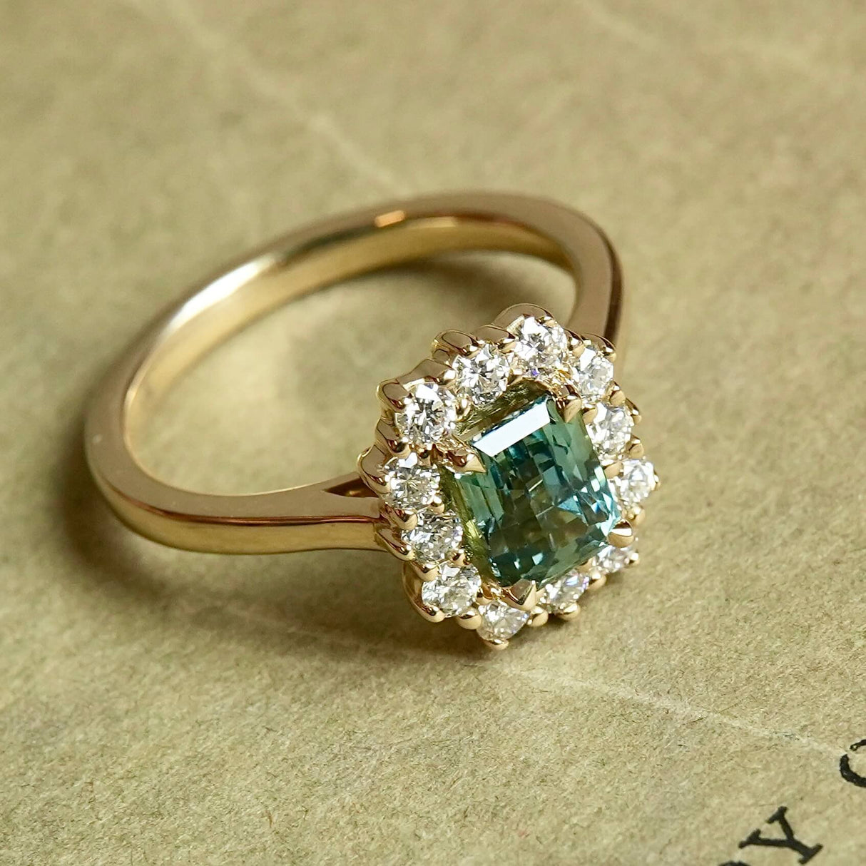 Green sapphire diamond cluster engagement ring in yellow gold setting