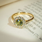 Green sapphire engagement ring with round centre stone and diamond halo cluster