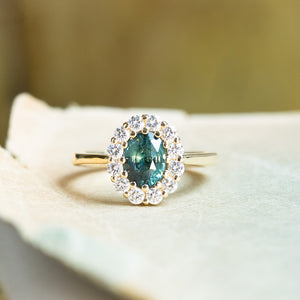 Antique inspired green sapphire and diamond cluster engagement ring with oval sapphire and diamond halo.