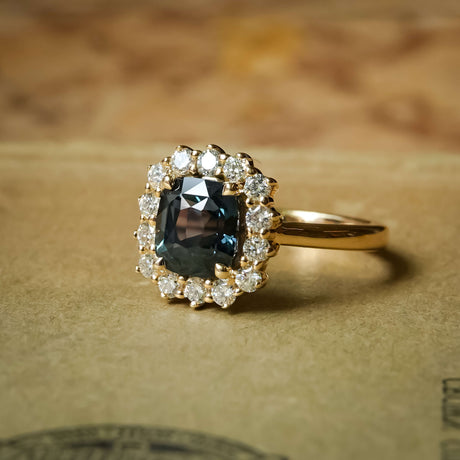Green sapphire and diamond cluster halo engagement ring in yellow gold setting