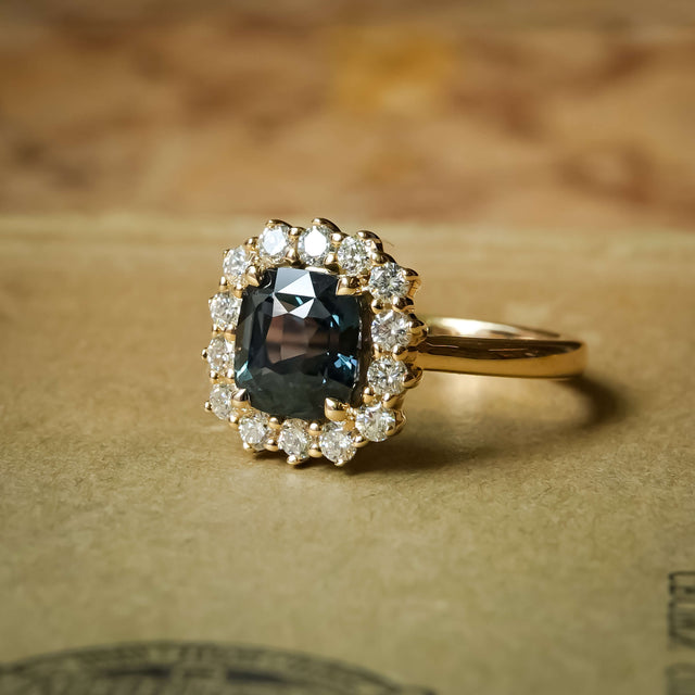 Green sapphire and diamond cluster halo engagement ring in yellow gold setting