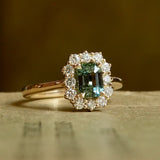 Green sapphire centre stone engagement ring with diamond halo cluster in yellow gold