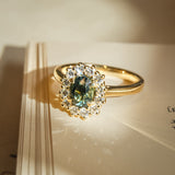 Green sapphire ring with oval gemstone and diamond cluster halo in gold