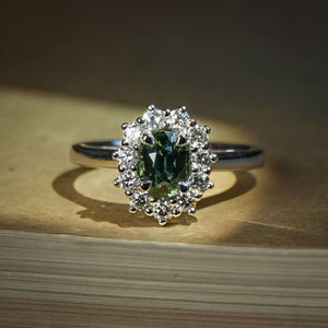 Green sapphire ring with oval gemstone and diamond cluster halo