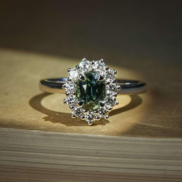 Green sapphire ring with oval gemstone and diamond cluster halo