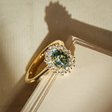Green sapphire engagement ring with oval gemstone and diamond cluster halo