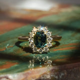 Oval green sapphire surrounded by diamond cluster engagement ring