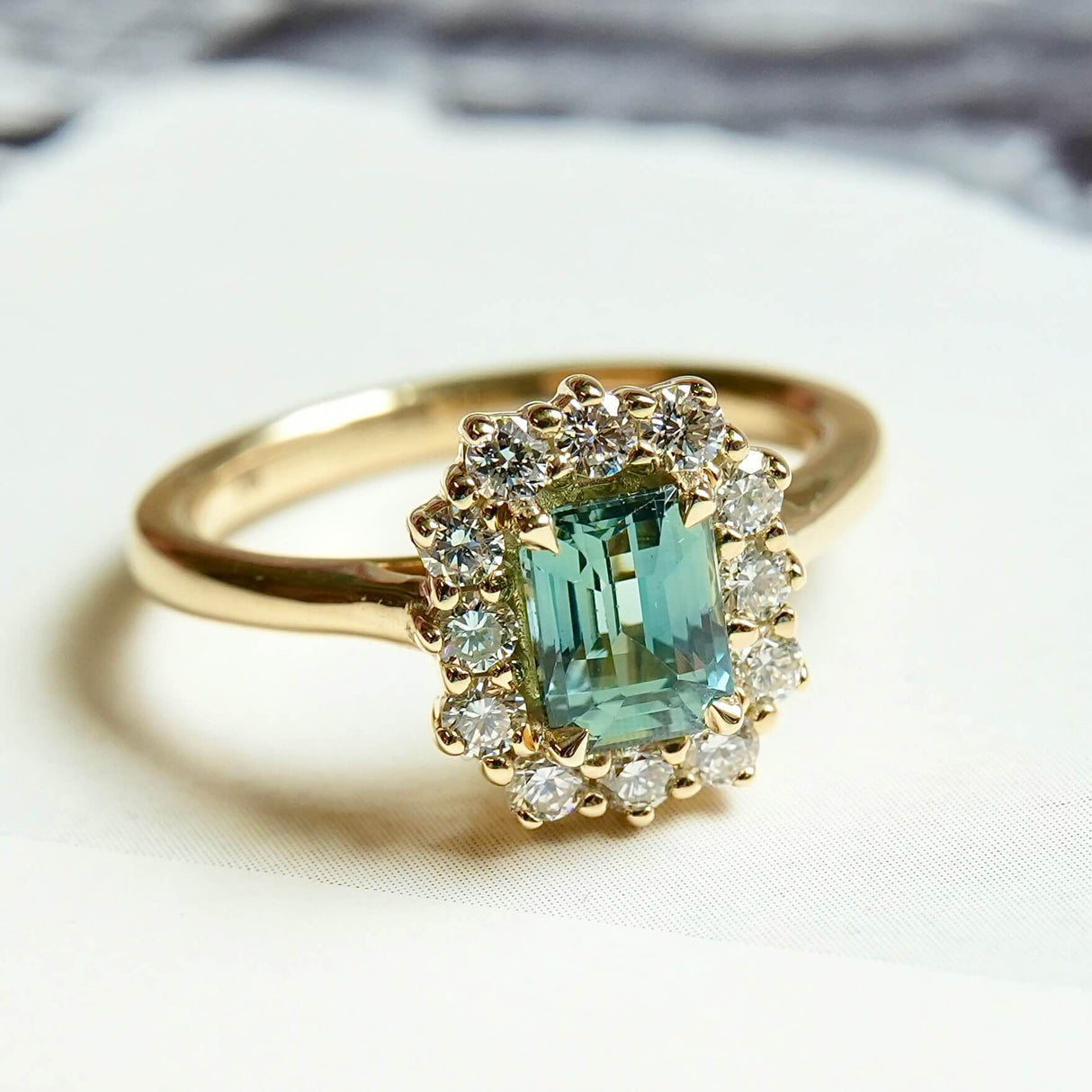 Emerald cut green sapphire engagement ring with diamond halo in yellow gold