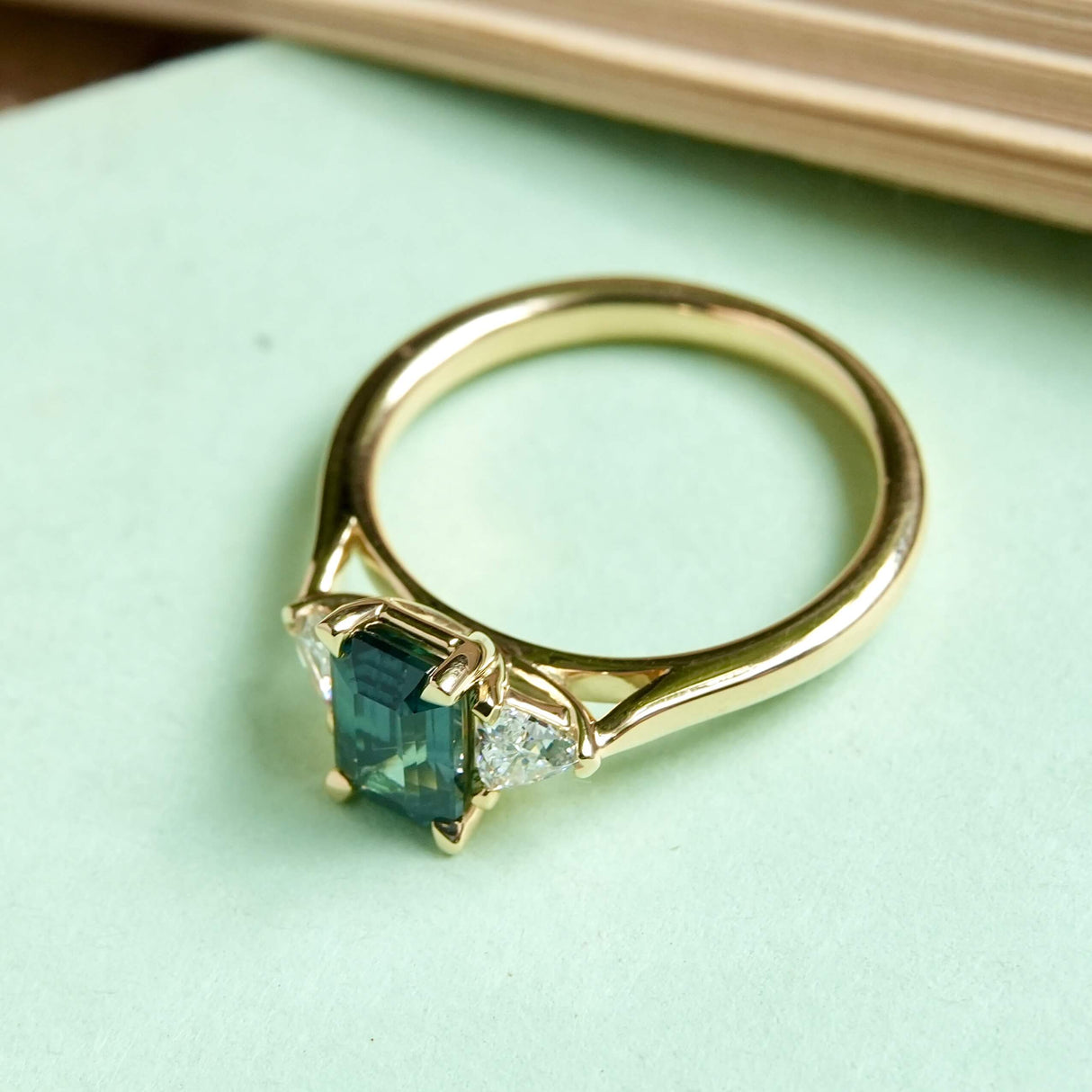 Green sapphire and diamond three stone engagement ring with yellow gold band