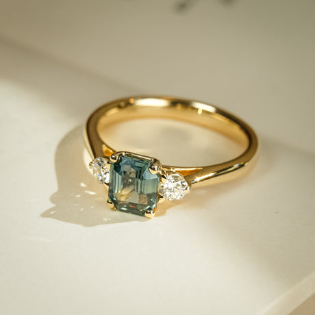 Green sapphire and diamond three stone engagement ring in yellow gold