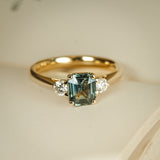 Green sapphire and diamond three stone engagement ring with yellow gold band