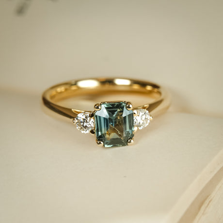 Green sapphire and diamond three stone engagement ring with yellow gold band