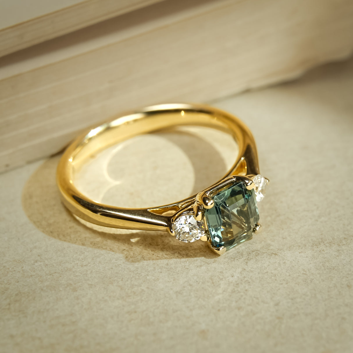 Green sapphire and diamond three stone engagement ring with gold band