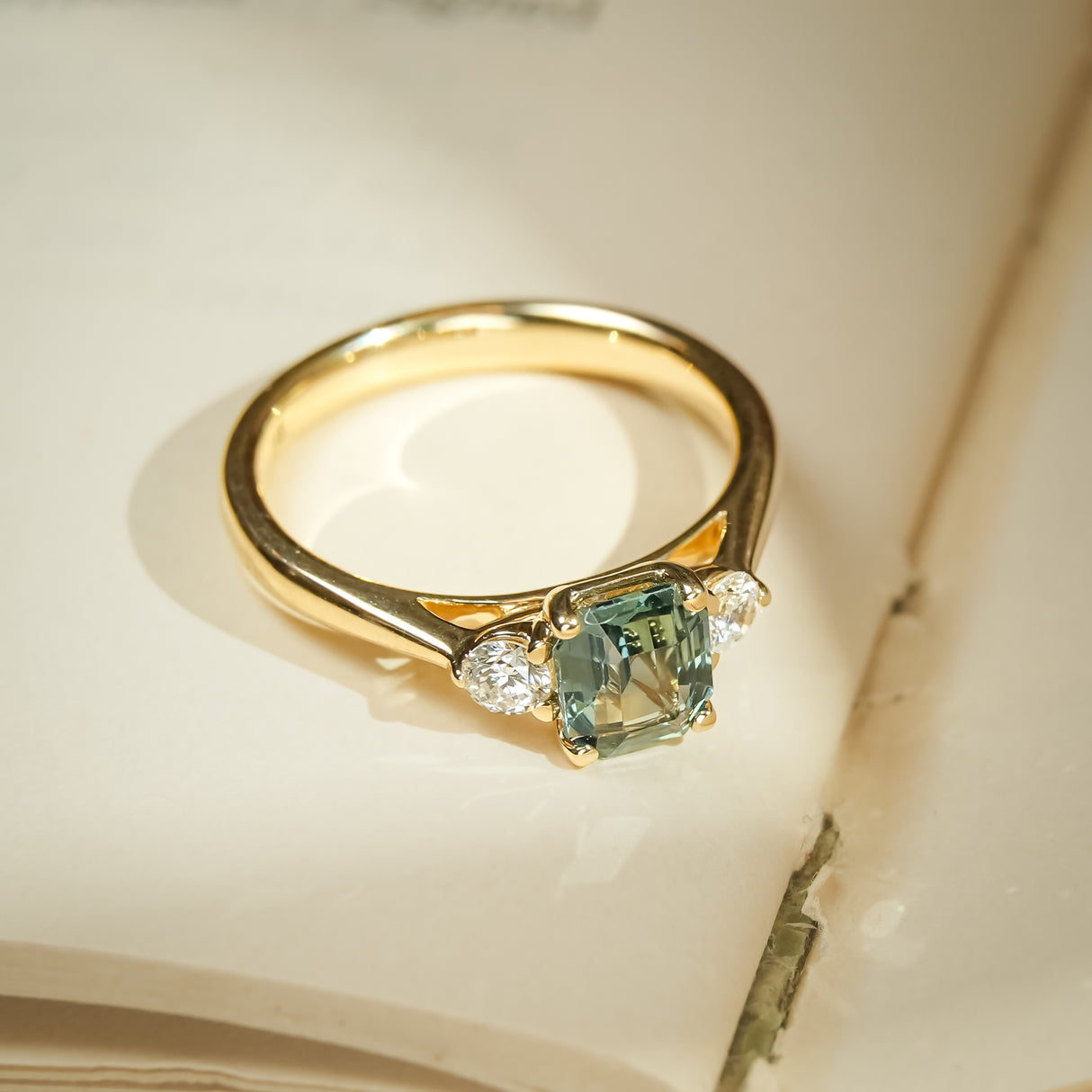 Green sapphire and diamond three stone engagement ring in gold setting