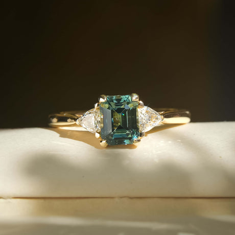 Green sapphire and diamond three stone engagement ring in yellow gold band