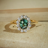 Oval green sapphire halo diamond engagement ring in yellow gold