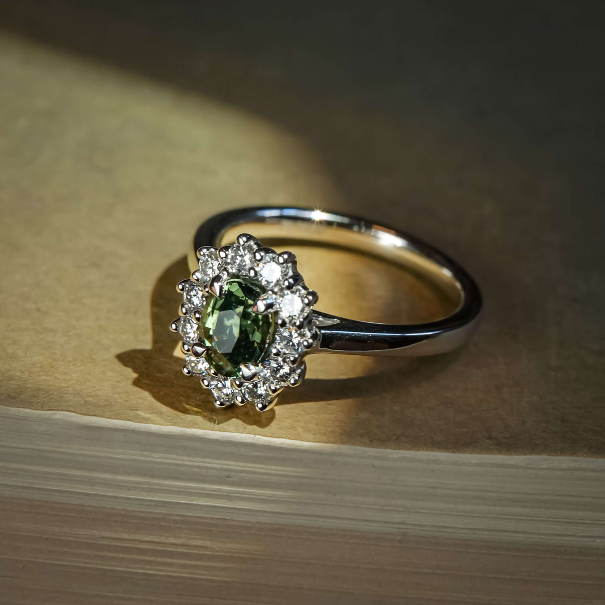 Green sapphire ring with oval gemstone and diamond cluster halo design