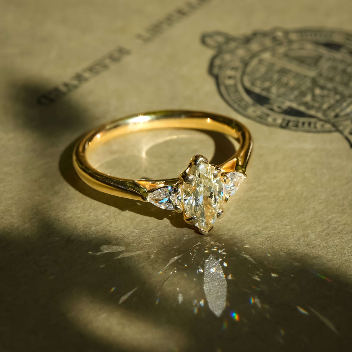 Marquise cut diamond and side diamonds three stone engagement ring in classic yellow gold