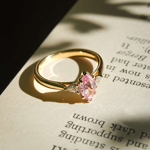 Marquise cut padparadscha pink sapphire and diamond three stone engagement ring in yellow gold band