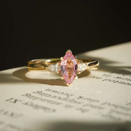 Marquise padparadscha pink sapphire with diamond three stone engagement ring in yellow gold