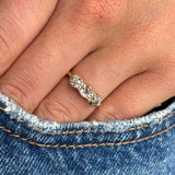 Antique Edwardian three-stone diamond ring in yellow gold styled on hand against blue denim, showcasing old-cut brown, pink and champagne coloured diamonds with subtle antique brilliance.