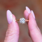 Cushion old-mine cut diamond solitaire engagement ring with square cushion diamond held between fingers.
