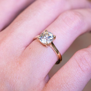 Cushion old-mine cut diamond solitaire engagement ring with gold band and raised solitaire setting.