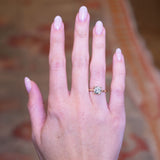 Cushion old-mine cut diamond solitaire engagement ring worn on hand with gold band.