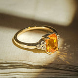 Orange sapphire ring with cushion cut gemstone and diamond trefoil cluster in gold