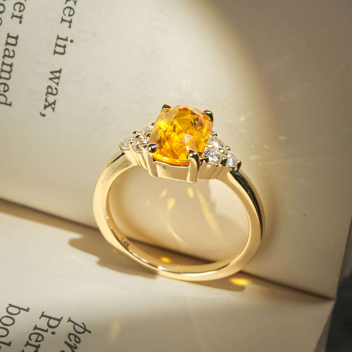 Orange sapphire ring with cushion cut gemstone and diamond trefoil cluster design