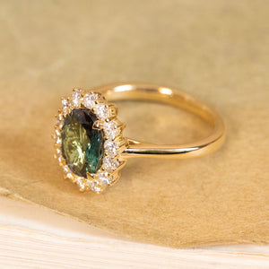 Oval green alexandrite and diamond cluster ring with a vivid central gemstone and bright diamond surround set in yellow gold.