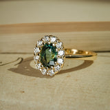 Oval green sapphire surrounded by diamond cluster in yellow gold ring