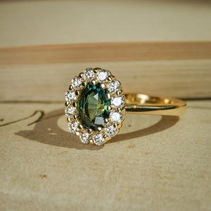 Oval green sapphire surrounded by diamond cluster in yellow gold ring