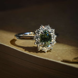 Oval green sapphire engagement ring with diamond cluster halo setting