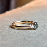 Yellow gold three-stone engagement ring with oval Sri Lankan green sapphire centre and diamond side stones.