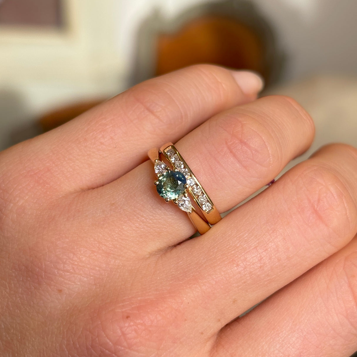 Wed-fit oval green sapphire and diamond three-stone engagement ring styled with a yellow gold wedding band.