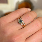 Wed-fit oval green sapphire and diamond three-stone engagement ring styled with a yellow gold wedding band.