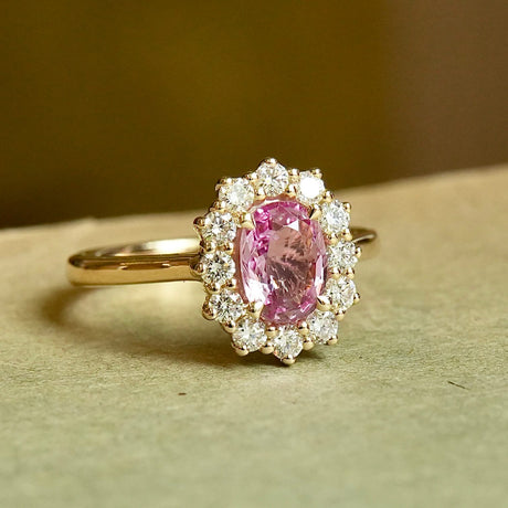 Oval padparadscha pink sapphire engagement ring with diamond cluster setting