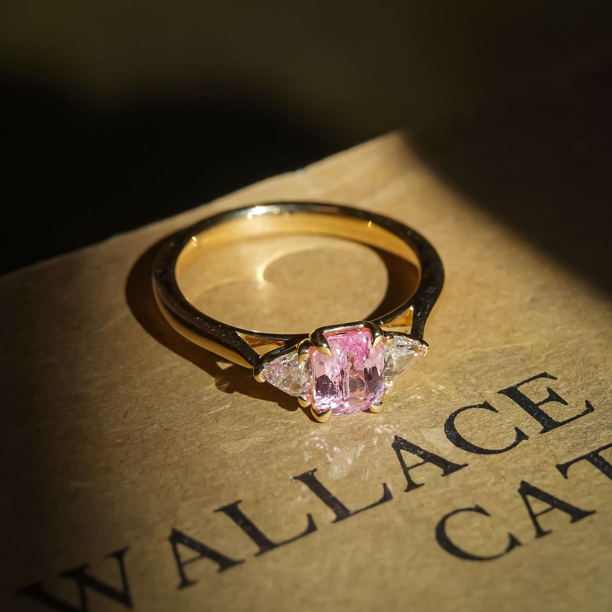 Oval padparadscha sapphire and diamond three stone engagement ring in yellow gold