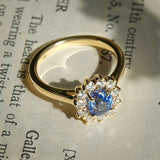 Oval royal blue sapphire with diamond cluster halo engagement ring in yellow gold
