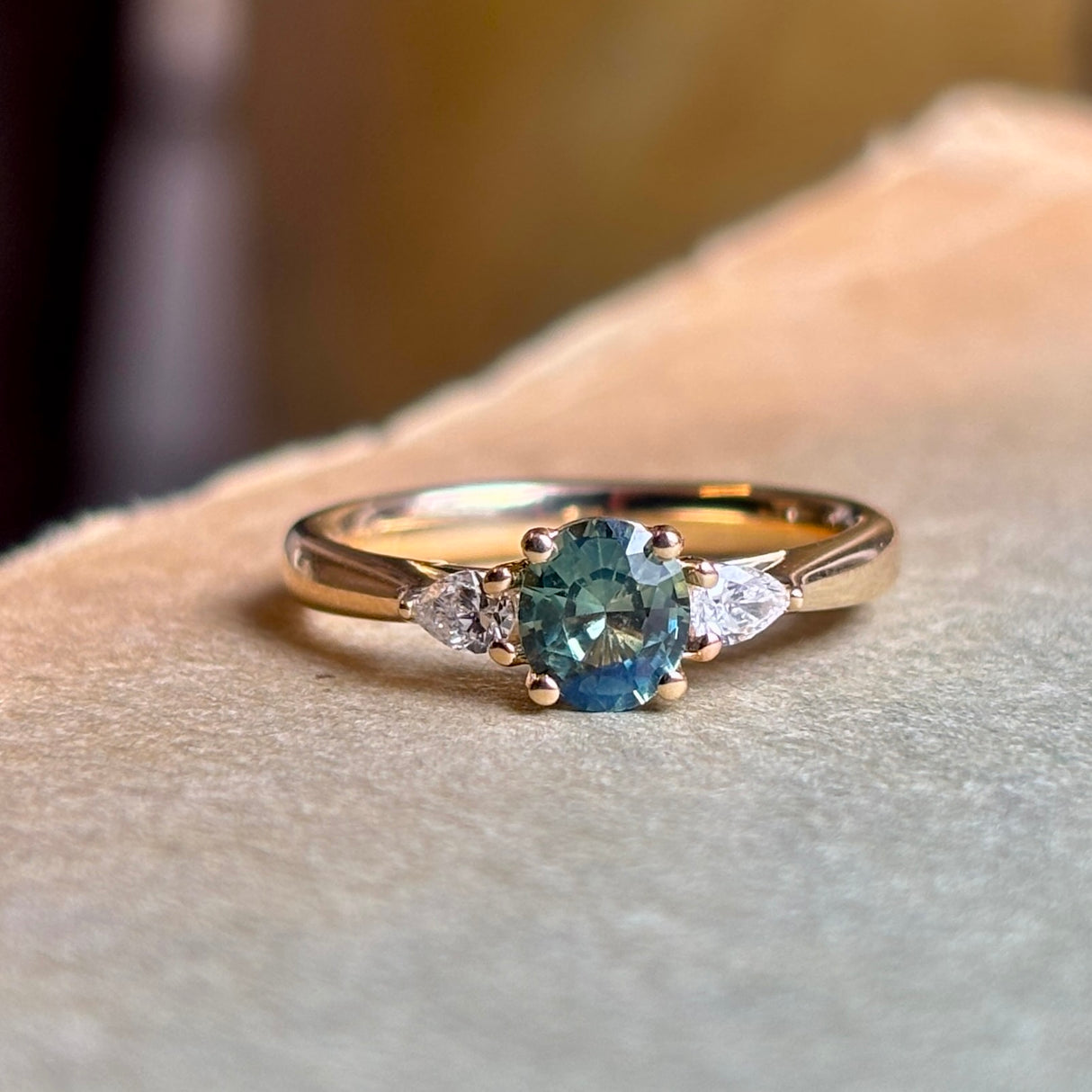 Oval Sri Lankan green sapphire engagement ring with diamond side stones in yellow gold.
