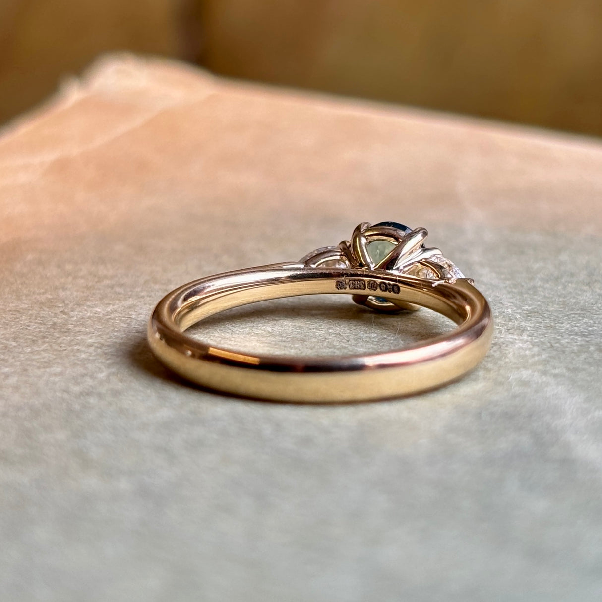 British hallmarks inside the band of the oval Sri Lankan green sapphire and diamond three-stone engagement ring.