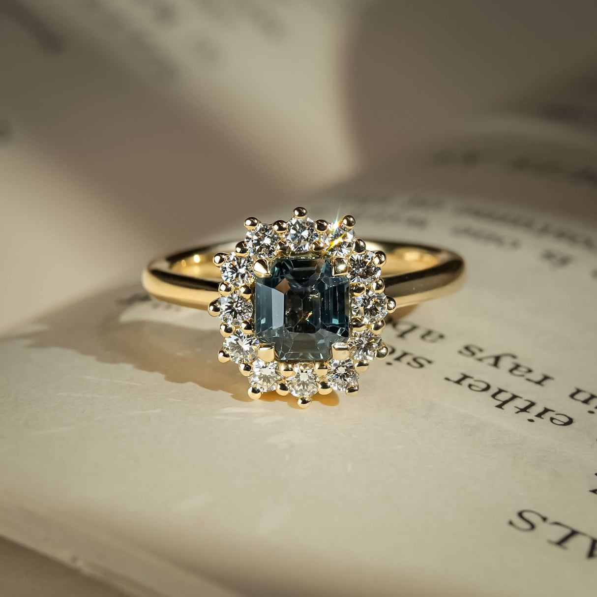 Oval teal sapphire ring with diamond cluster halo setting